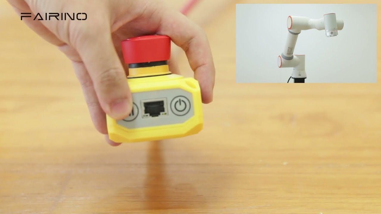 Operator trzyma button box FAIRINO z wyłącznikiem awaryjnym przy robocie.